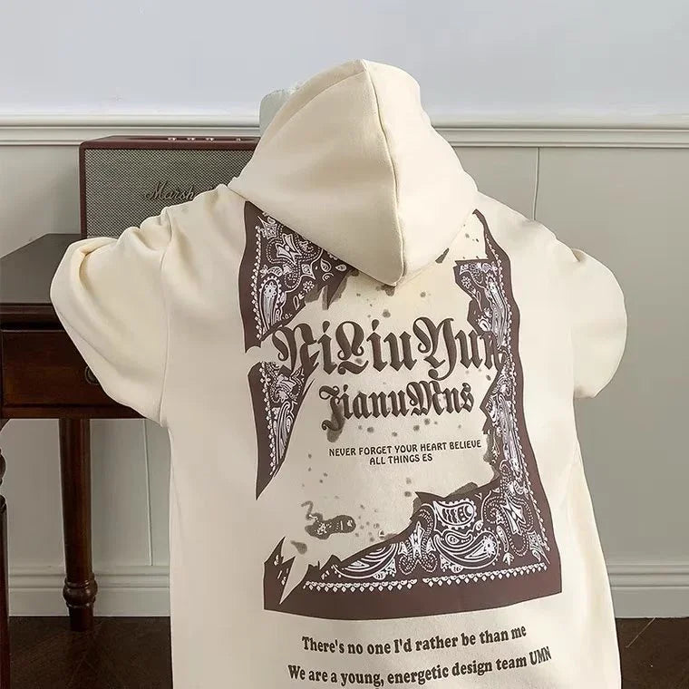Beige hoodie with intricate brown bandana print and Gothic text in a modern room
