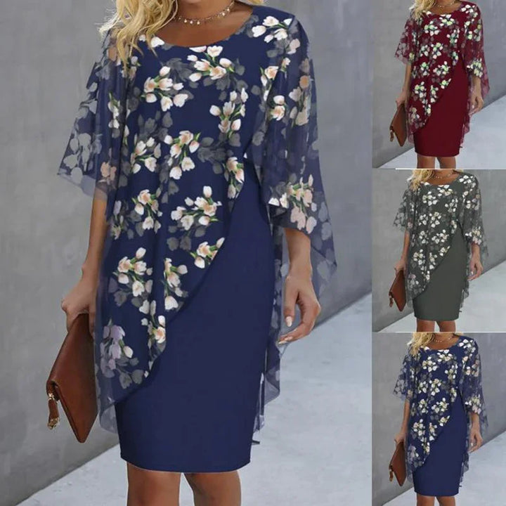 Woman wearing floral print overlay midi dress in navy, red, and gray, holding brown clutch purse