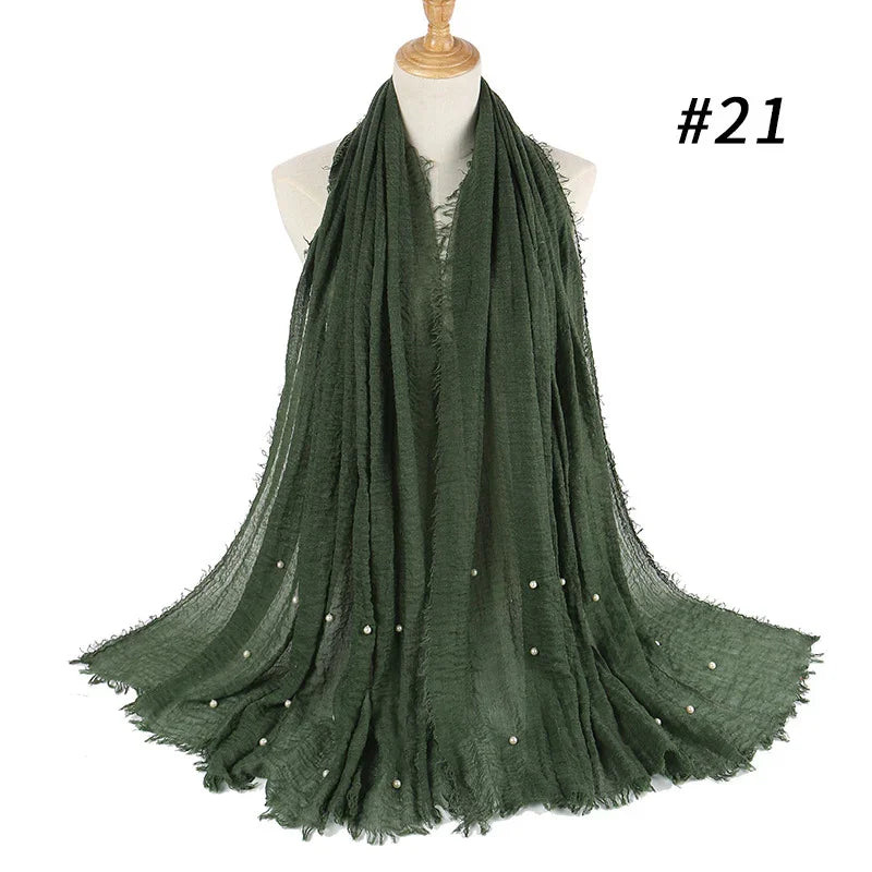 Dark green lightweight scarf with fringed edges and small pearl embellishments displayed on a mannequin