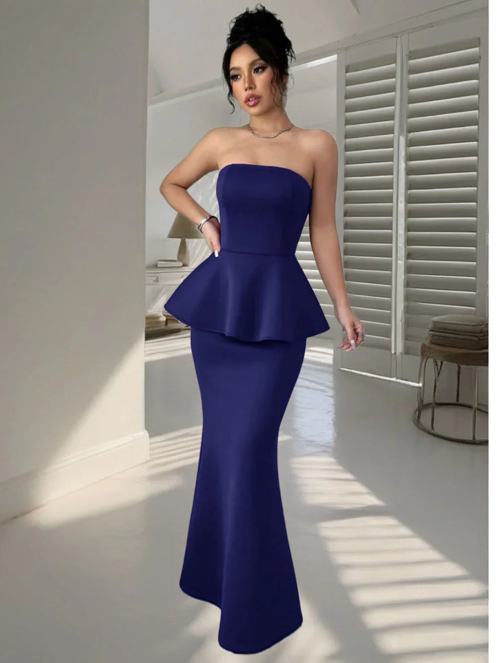 Woman in elegant strapless navy blue peplum evening gown in modern minimalist room