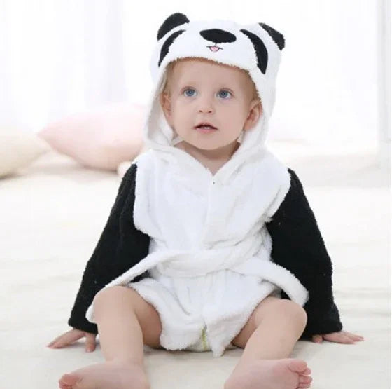 Baby wearing a cozy white and black panda hooded onesie sitting on a soft floor in bright room