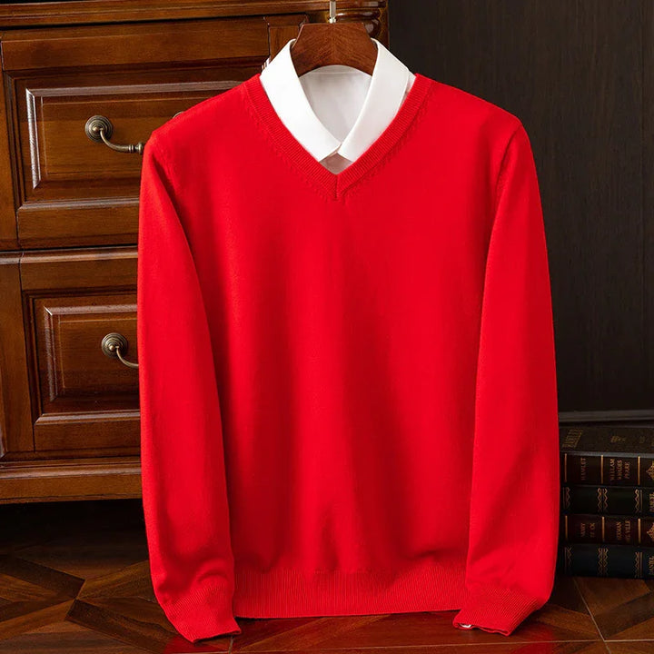 Red V-neck sweater layered over white collared shirt on wooden hanger with vintage furniture background