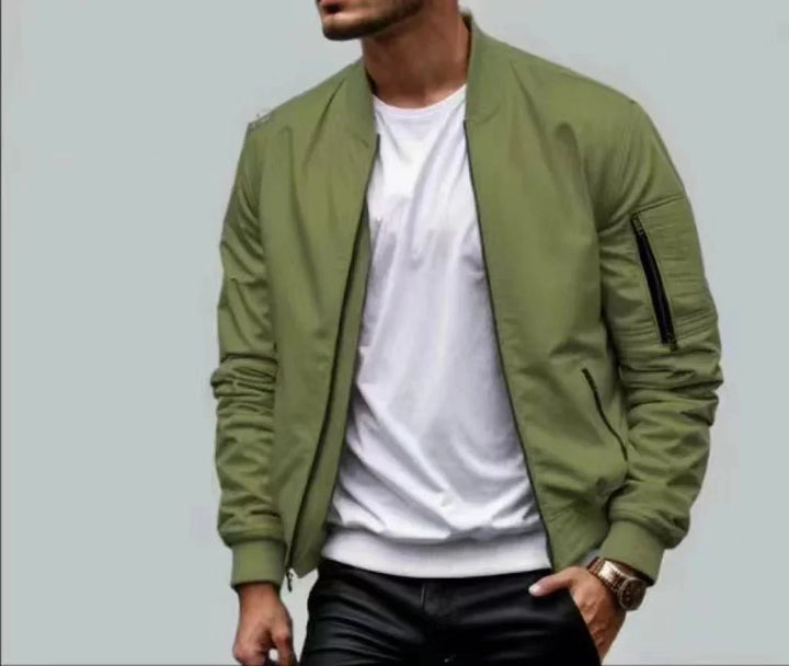 Man wearing olive green bomber jacket over white t-shirt and black pants with watch on wrist
