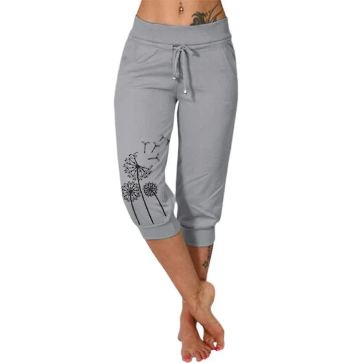 Woman wearing gray capri sweatpants with black dandelion print and drawstring waist