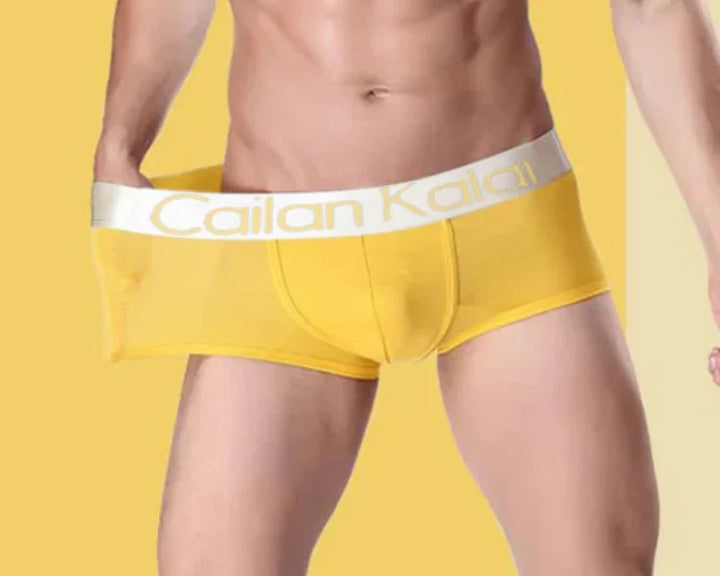 male model wearing yellow Cailan Kaiai men's underwear with white waistband against yellow background