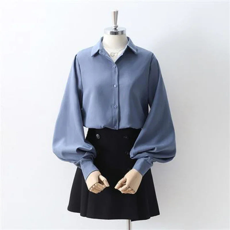 Blue button-up blouse with puffed long sleeves paired with black high-waisted mini skirt on mannequin