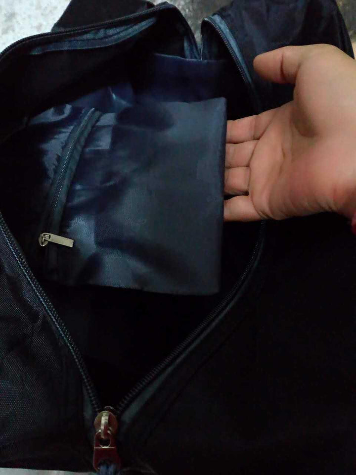 Hand opening pocket inside black travel bag with zipper pouch