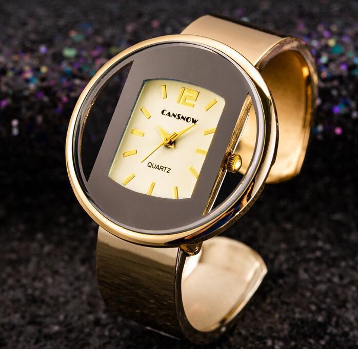 Gold-toned CANSNOW quartz ring watch with a unique round black and gold face on a dark glittery background