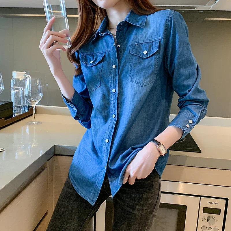 Woman wearing blue denim shirt and black jeans holding a glass of water in modern kitchen