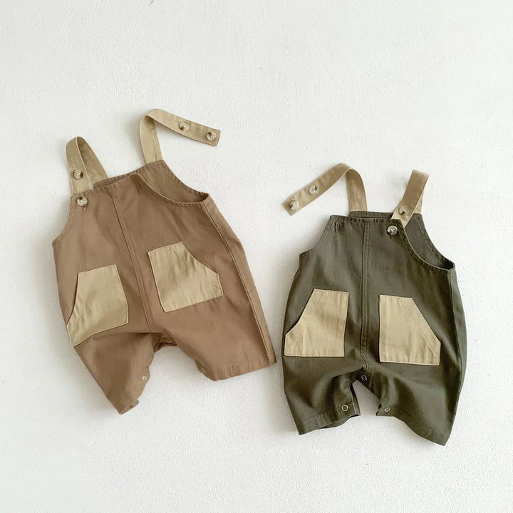 Two baby romper overalls in brown and olive green with beige pockets and adjustable shoulder straps