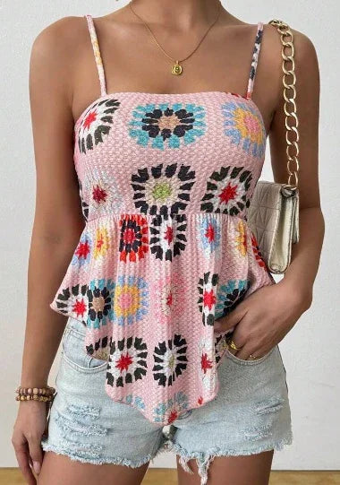 Woman wearing pink floral sleeveless top with asymmetrical hem and light blue distressed denim shorts