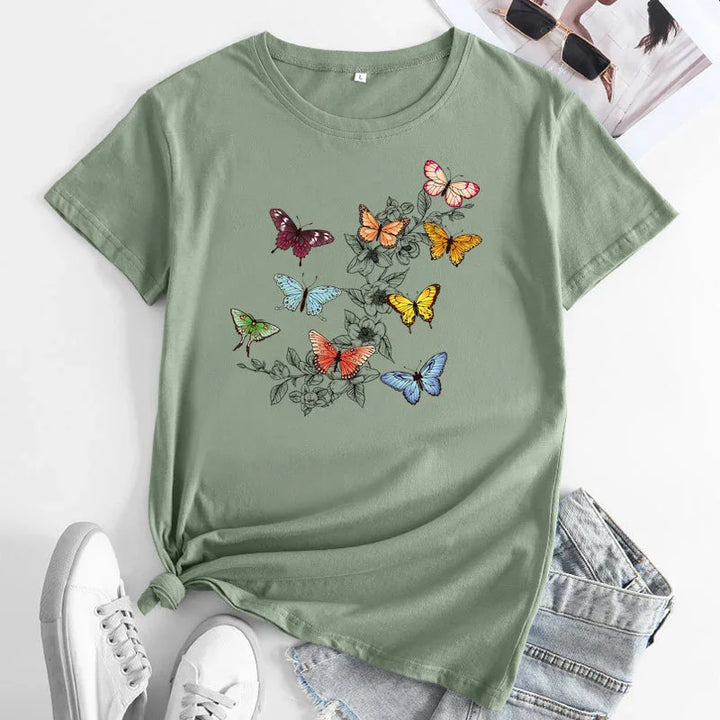 Light green t-shirt with colorful butterfly and floral print, styled with denim shorts and white sneakers