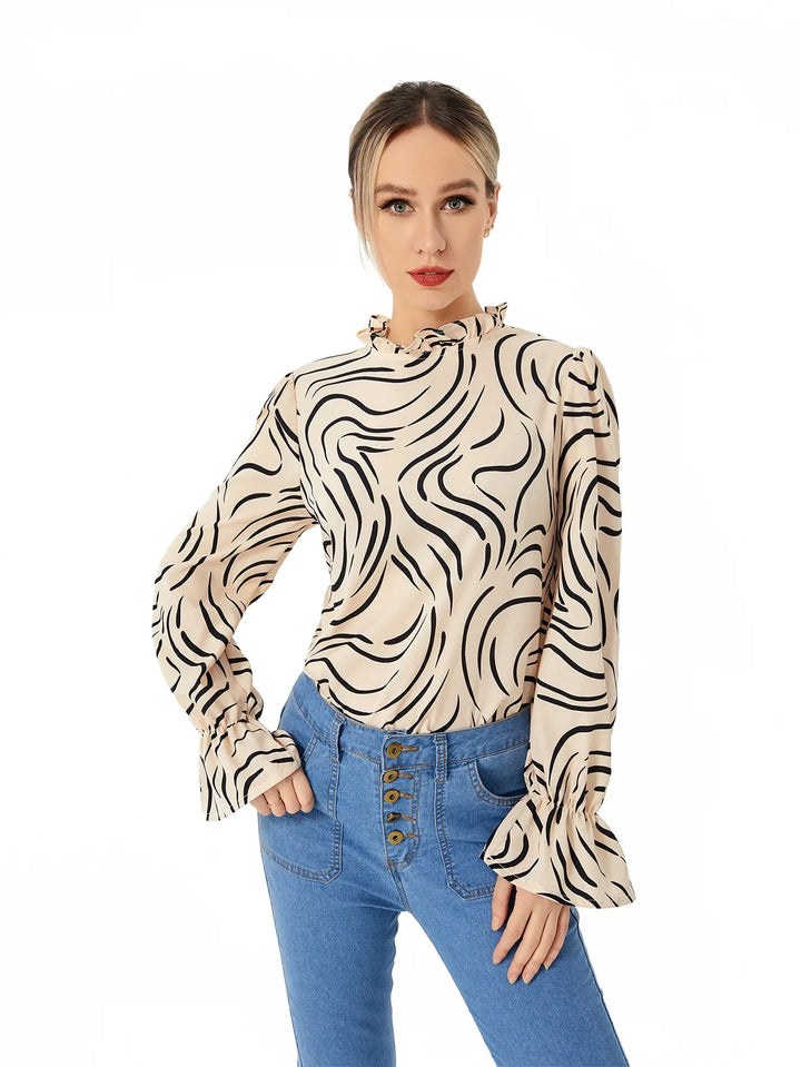 Woman wearing beige long-sleeve blouse with black swirl print and blue high-waisted jeans