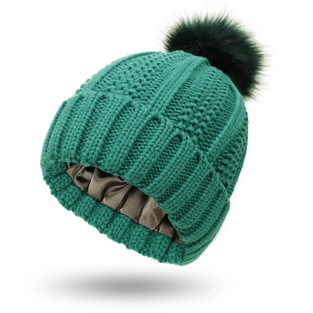Green knitted winter beanie with black faux fur pompom and inner satin lining