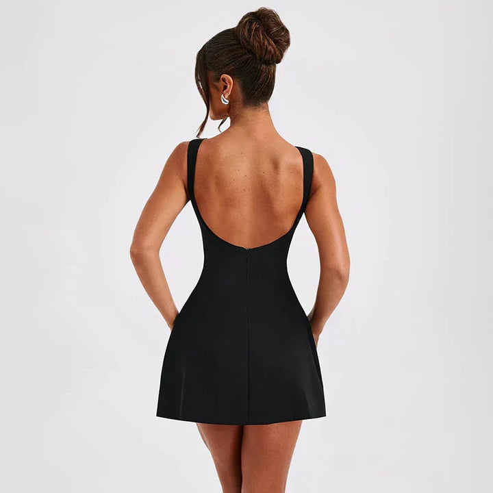 Woman wearing a black sleeveless mini dress with an open back and hair in a bun