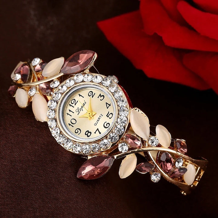 Elegant gold-tone watch with crystal and purple gemstone accents on dark fabric with red rose