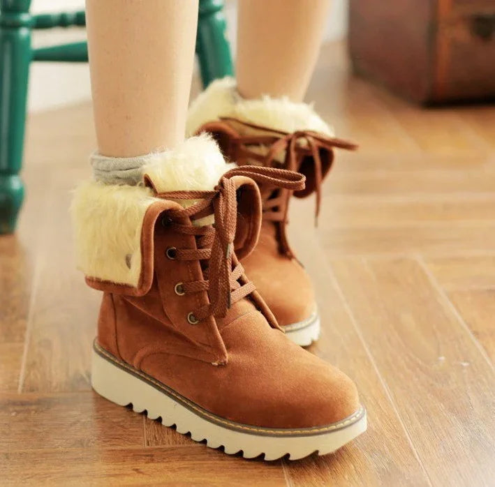 Brown suede winter boots with white fur cuffs and thick soles worn on hardwood floor