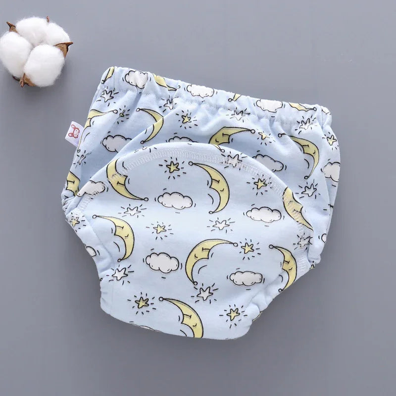 Light blue baby training pants with yellow moons, stars, and clouds print on gray background with cotton boll