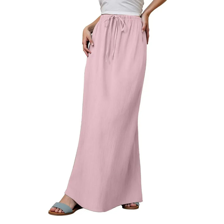 Woman wearing a light pink drawstring waist maxi skirt with pockets and blue sandals