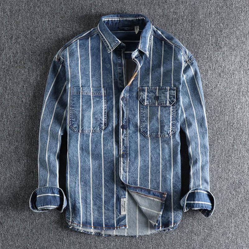 Blue denim shirt with white vertical stripes and dual chest pockets on gray surface