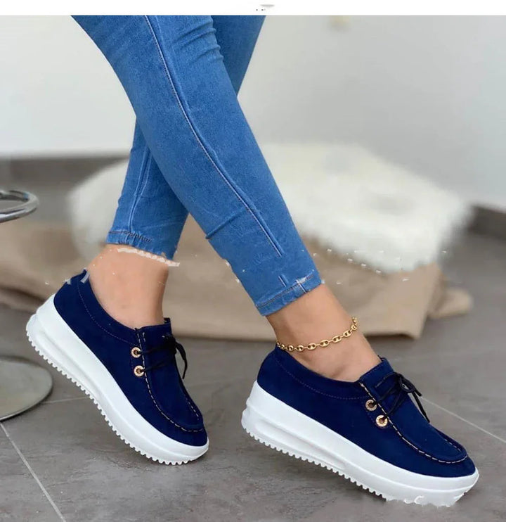 Woman wearing blue casual lace-up platform sneakers with white soles and blue jeans