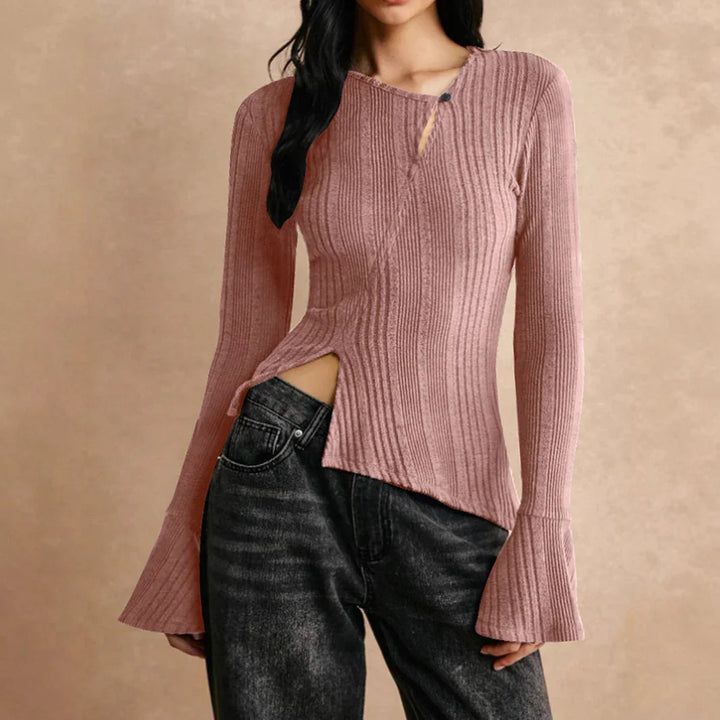 Woman wearing asymmetrical dusty pink ribbed knit sweater with flared sleeves and black jeans