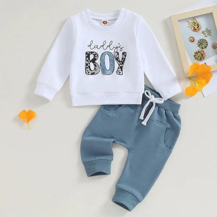 White long-sleeve baby sweatshirt with 'Daddy's Boy' text and blue pants set on white background