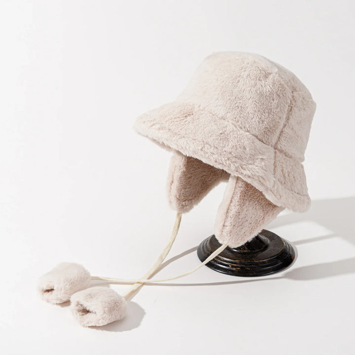 Soft beige faux fur bucket hat with ear flaps and pom pom ties on display stand