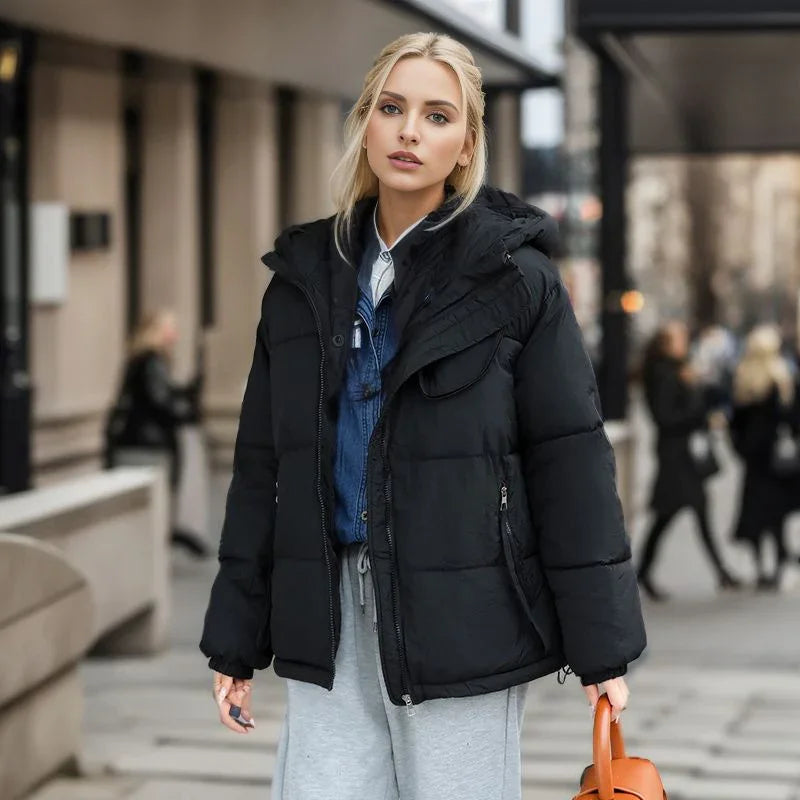Blonde woman wearing a black puffer jacket and gray sweatpants walking in urban street