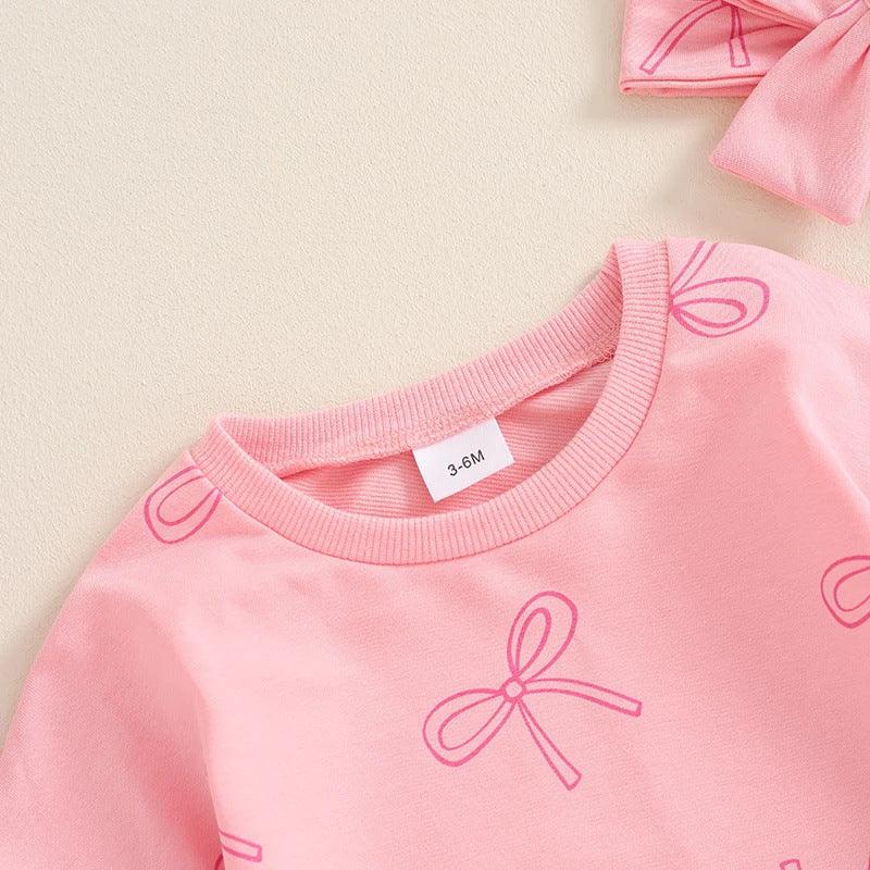 Pink baby shirt with bow prints and matching headband on beige background, size 3-6 months