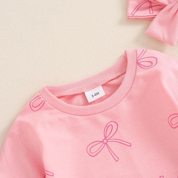 Pink baby shirt with bow prints and matching headband on beige background, size 3-6 months