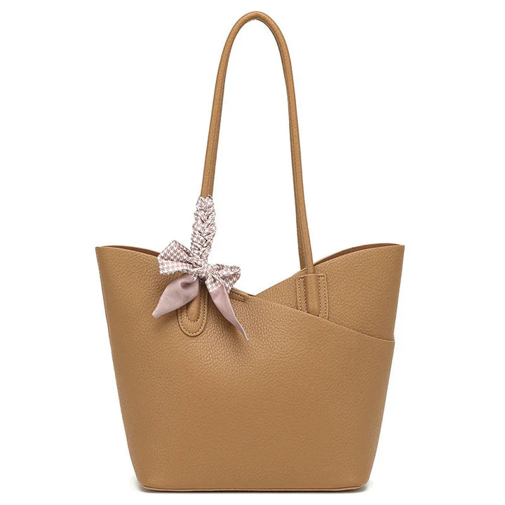 Tan textured leather tote bag with thin shoulder straps and a pink patterned scarf tied on one strap