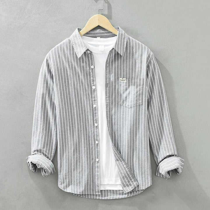 Gray and white striped casual button-up shirt layered over a plain white T-shirt on a wooden hanger