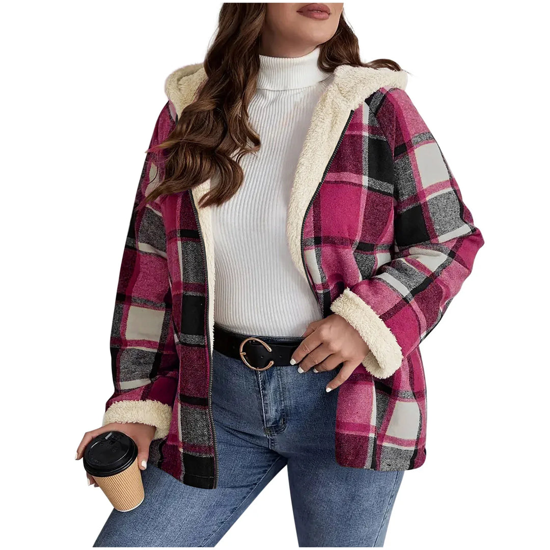Woman wearing pink plaid hooded jacket with fleece lining, white turtleneck, blue jeans, holding coffee cup