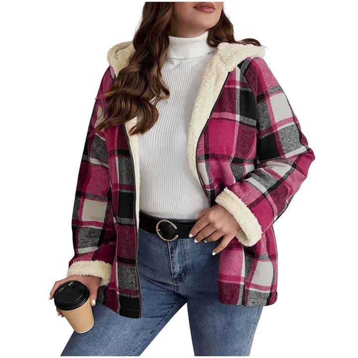 Woman wearing pink plaid hooded jacket with fleece lining, white turtleneck, blue jeans, holding coffee cup