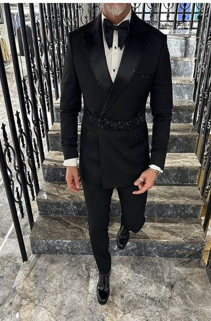 Man dressed in a stylish black tuxedo with bow tie, walking up marble stairs with decorative black railings