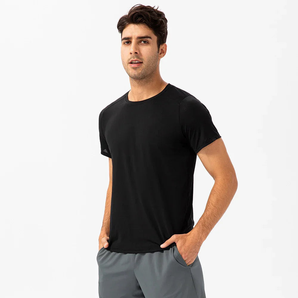 Man in black crew neck t-shirt and gray shorts posing against white background