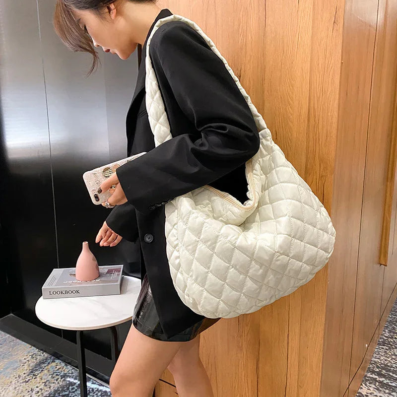 Woman in black blazer carrying large quilted white shoulder bag indoors