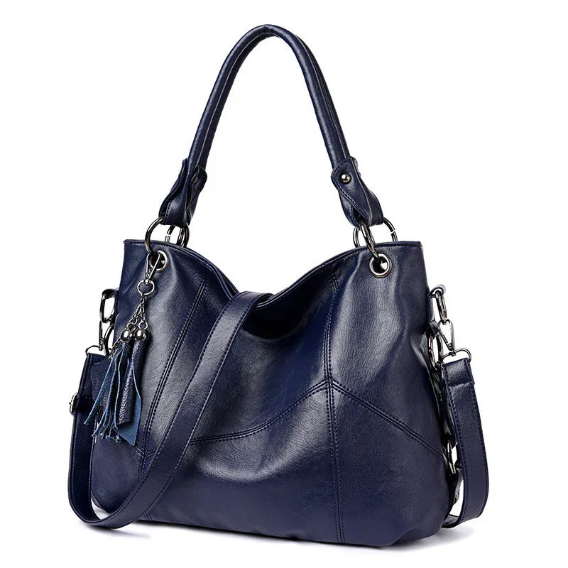 Navy blue leather handbag with dual handles, detachable shoulder strap, and tassel charm
