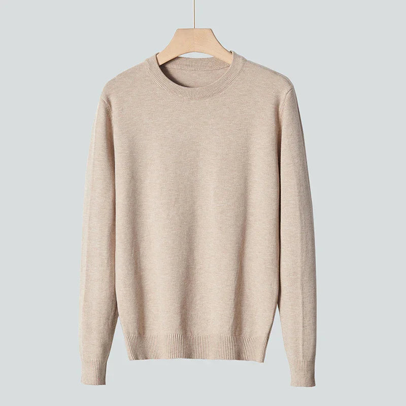 Beige crewneck sweater hanging on wooden hanger against gray background, casual knitwear
