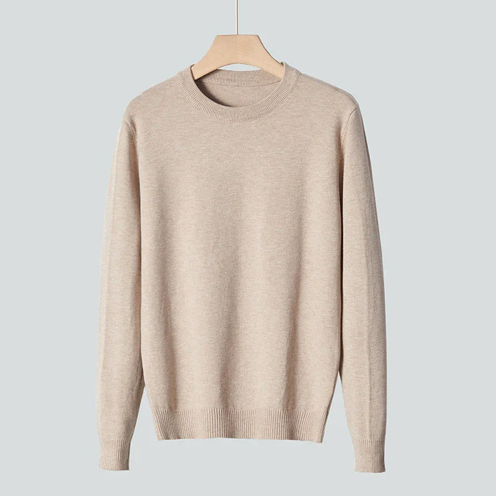 Beige crewneck sweater hanging on wooden hanger against gray background, casual knitwear