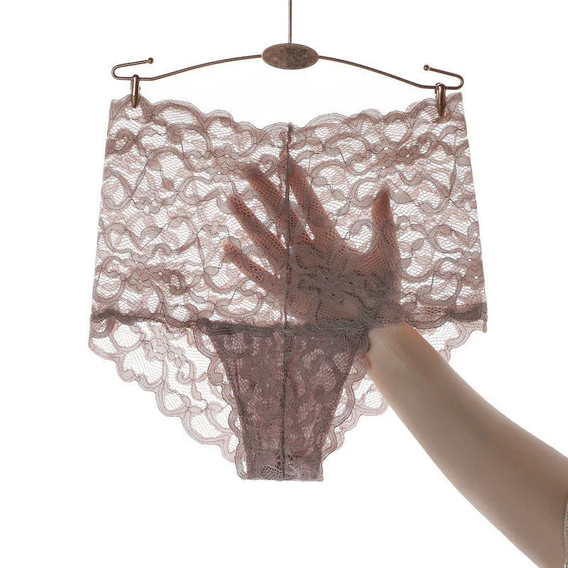 Hand holding sheer pink lace lingerie underwear on metal hanger against white background
