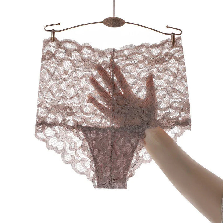 Hand holding sheer pink lace lingerie underwear on metal hanger against white background