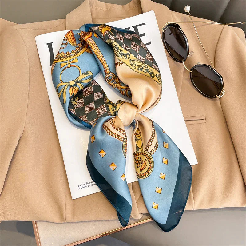 Silk patterned scarf with blue, gold, and beige tones on beige blazer and fashion magazine, with black sunglasses