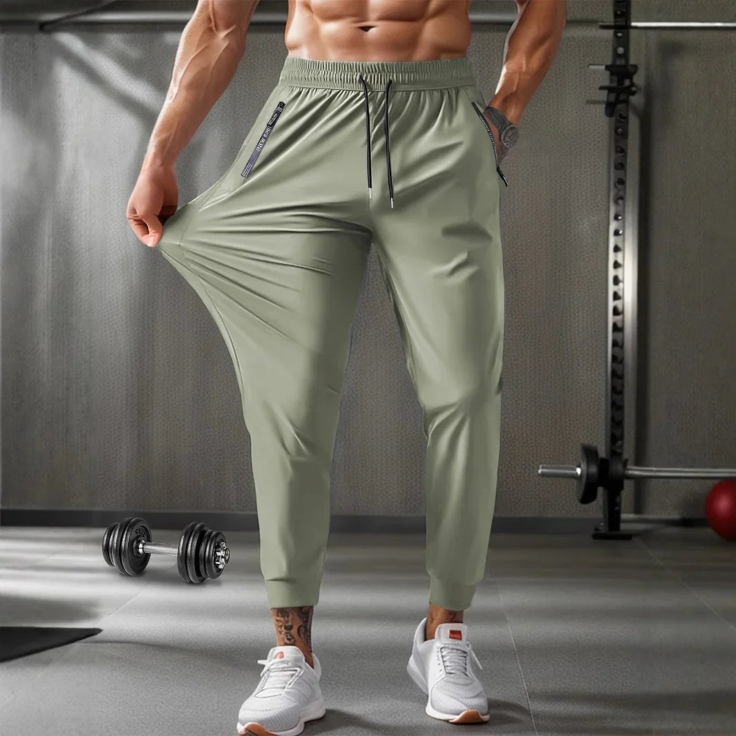 Muscular man in gym wearing light green stretchable jogger pants and white sneakers, holding fabric