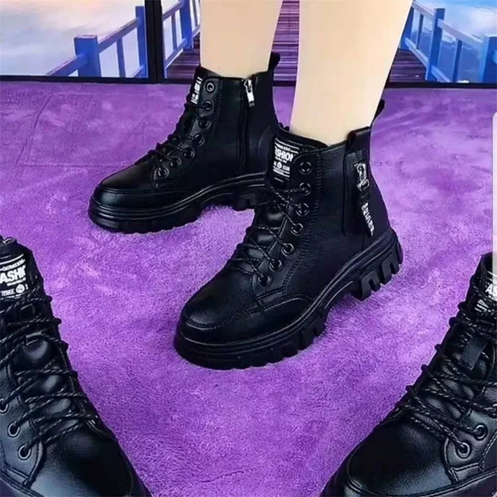Black lace-up combat boots with zipper and thick sole worn on light skin, standing on purple carpet