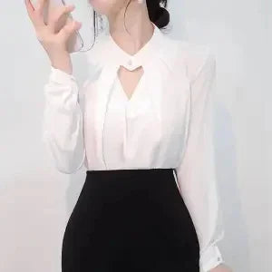 Woman wearing white blouse with heart-shaped cutout and black high-waist skirt taking a selfie