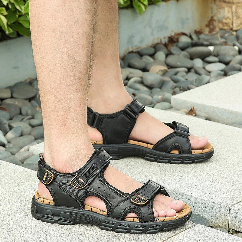 Men's black leather outdoor sandals with adjustable straps on stone pavement