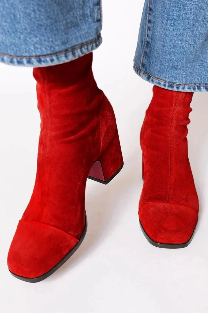 Close-up of red suede ankle boots with block heels worn with blue denim jeans