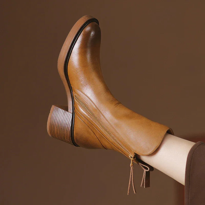 Tan leather ankle boot with stacked heel and side zipper on brown background